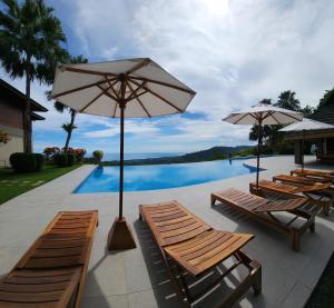 un groupe de chaises et de parasols à côté d'une piscine dans l'établissement Lamangata Luxury Surf Resort, à Dominical
