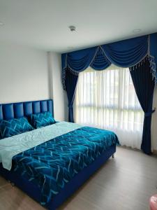 a bedroom with a blue bed with blue sheets and windows at supalai city resort in Ban Khlong Samrong