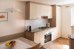 a kitchen with white cabinets and a table with a bowl of fruit at Apartment Pössnecker in Selva di Val Gardena