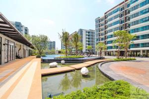 Ban Khlong Samrong的住宿－supalai city resort，一座有楼房的城市中,有一座庭院,里面设有池塘