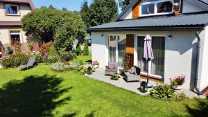 a garden with a house with a umbrella and a lawn at Apartamenty Jagodzianka - Jacuzzi, Sauna, Hot-bania, Tężnia in Ustrzyki Dolne