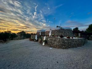 a stone wall next to a building with a sunset in the background at Trulli delle succulente in Capilungo