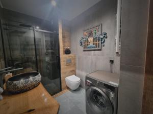 a bathroom with a sink and a washing machine at Apartament Madlen Art in Olecko