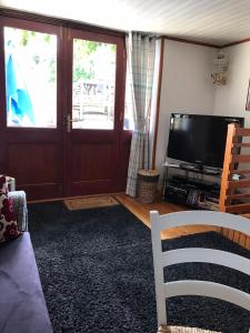 a living room with a flat screen tv and a couch at Cottage Les Glycines in Javron-Les-Chapelles