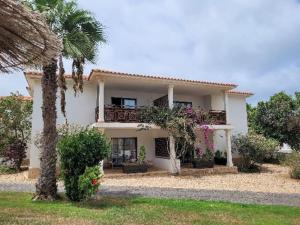 a white house with a balcony and a palm tree at Tortuga beach lovely 2 bed apartment and gardens in Santa Maria
