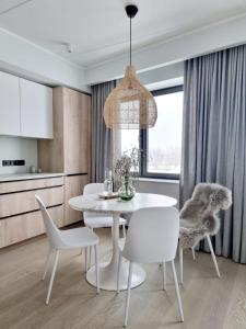 uma sala de jantar com uma mesa branca e cadeiras brancas em Hilltop Apartments - Kiikri Residence City Centre em Talin