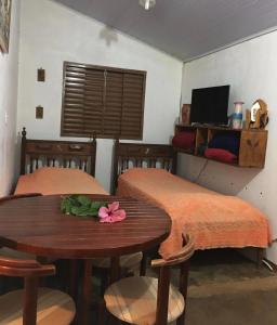 een kamer met 2 bedden en een tafel met bloemen erop bij Residencial Recanto do Sabiá in Alto Paraíso de Goiás