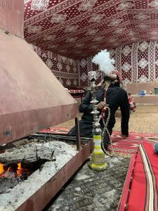 a man sitting next to a fire in a room at Wadirum winter in Wadi Rum