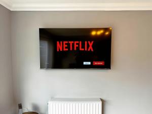 einen TV an einer Wand mit einem Netflix-Schild drauf in der Unterkunft New Stylish 2 Bedroom House in Kent