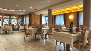 - un restaurant avec des tables et des chaises dans une salle dans l'établissement Hotel Regent's, à Andalo