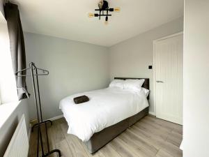 um pequeno quarto com uma cama com lençóis brancos em New Stylish 2 Bedroom House em Kent