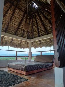 Cama en habitación con techo de paja y vistas al océano en Sunset Beachside Villa, en Puerto Escondido