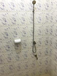 een douche in een badkamer met witte tegels bij RÉSIDENCE SYLOMÈNE in Godomè