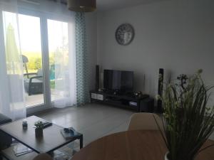 a living room with a table and a tv and a dining room at charmante maison au calme avec jardin, terrasse et jacuzzi in Barjouville