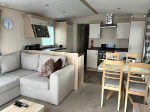 a living room and kitchen with a couch and a table at Memories Made, Quiet Holiday, Green Lawns in Selsey