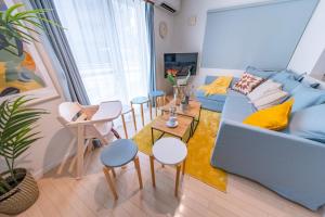 HOTEL Flag Tokyo - Vacation STAY 29759v في طوكيو: غرفة معيشة مع أريكة زرقاء وطاولة وكراسي