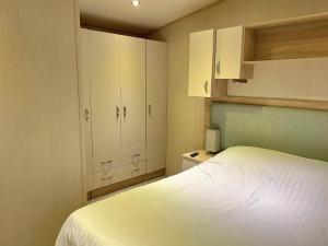 a small bedroom with a white bed and cabinets at Memories Made, Quiet Holiday, Green Lawns in Selsey