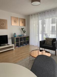 een woonkamer met een bank, een tafel en een televisie bij Gemütliches City Apartment in Friedrichshafen