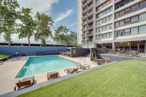 an outdoor swimming pool with chairs and a building at Downtown Tulsa Apartment - Near BOK Center! in Tulsa