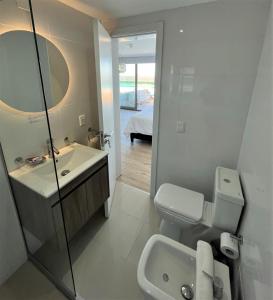 a bathroom with a sink and a toilet and a mirror at SYRAH Premium B1 - Piscina privada con vista al mar by depptö in Punta del Este