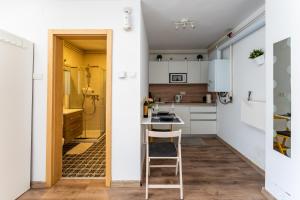 a small kitchen with white cabinets and a stool at Studio apartman Queen in Bjelovar