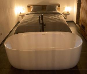 a white bath tub in front of a bed at Au p'tit cachot (Gîte insolite) in Vaux-sur-Sûre