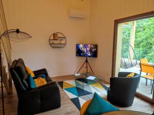 a living room with two chairs and a tv at Alsace Chalet & Spa Meyer-Krumb in Sigolsheim