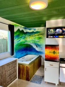 baño con una pintura de una bañera en Cabanas Prema, en Praia do Rosa