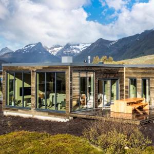 una casa de madera con montañas en el fondo en NEW! Luxury Cabin in beautiful Lofoten, en Kleppstad