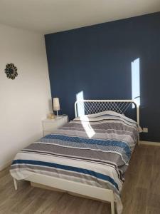 a bedroom with a bed with a blue wall at charmante maison au calme avec jardin, terrasse et jacuzzi in Barjouville