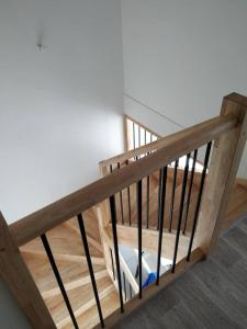 a wooden staircase with black railings in a room at charmante maison au calme avec jardin, terrasse et jacuzzi in Barjouville
