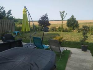 a patio with a table and chairs and an umbrella at charmante maison au calme avec jardin, terrasse et jacuzzi in Barjouville