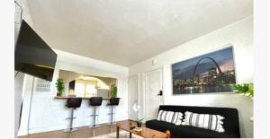 a living room with a black couch and a painting at (55.1S) Experience a True STL Visit! in Saint Louis