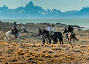 un grupo de gente montando caballos en el desierto en Estancia La Estela en Lago Viedma