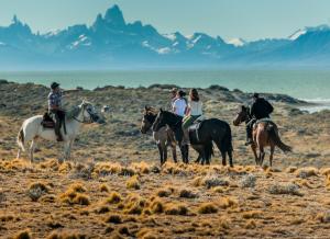 a group of people riding horses in the desert at Estancia La Estela in Lago Viedma