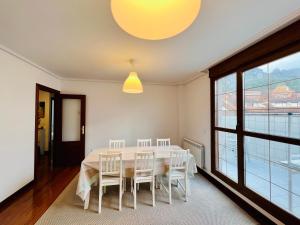 ein Esszimmer mit einem Tisch, Stühlen und einem Fenster in der Unterkunft Excelente apartamento con garaje y piscina in Ramales de la Victoria