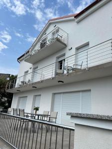 a white building with chairs and a balcony at Villa Laki Rab Studio App Teras in Banjol