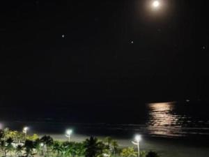 lua cheia sobre a água à noite em Magia e encanto na Praia Grande