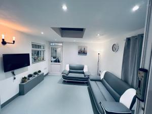 a living room with a couch and a tv at Four bedroom bungalows with private parkings in Sidcup