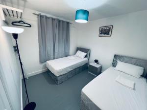 a bedroom with two beds and a lamp in it at Four bedroom bungalows with private parkings in Sidcup