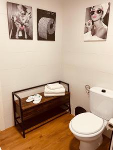 a bathroom with a toilet and pictures on the wall at Alojamiento Singular Casa Haraiz in Jaraiz de la Vera