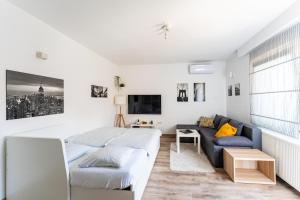 a white bedroom with a bed and a couch at Studio apartman the little Prince in Bjelovar