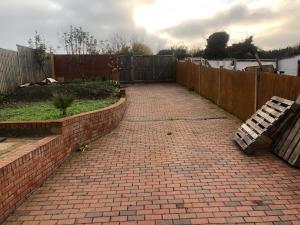 a brick driveway with a fence and a wooden bench at Four bedroom bungalows with private parkings in Sidcup