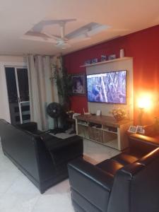 Casa com Belas vistas - Muriqui في مانغاراتيبا: غرفة معيشة مع أريكة وتلفزيون بشاشة مسطحة