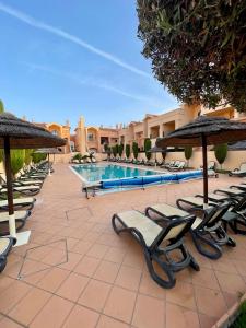 - une rangée de chaises et de parasols à côté de la piscine dans l'établissement E&M Apartment Luz, à Luz