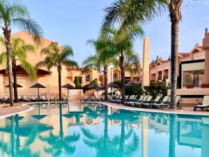 a pool at a resort with palm trees and chairs at E&M Apartment Luz in Luz
