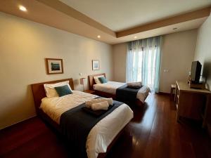Cette chambre comprend deux lits et une télévision. dans l'établissement E&M Apartment Luz, à Luz