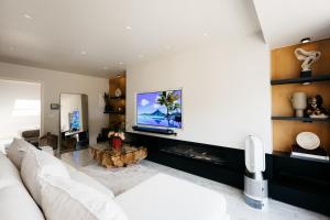 a living room with a white couch and a tv at The Edgewater Suites - RIVERSIDE in Namur