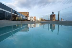 una piscina con un edificio e una torre dell'orologio di Hotel Aldama a Mérida