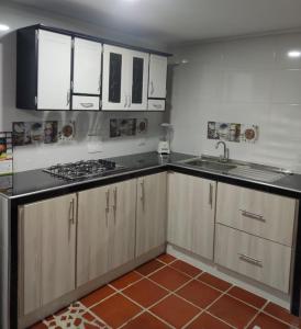 cocina con armarios blancos, fregadero y fogones en Apartamento amoblado nuevo en Guadalajara de Buga en Buga